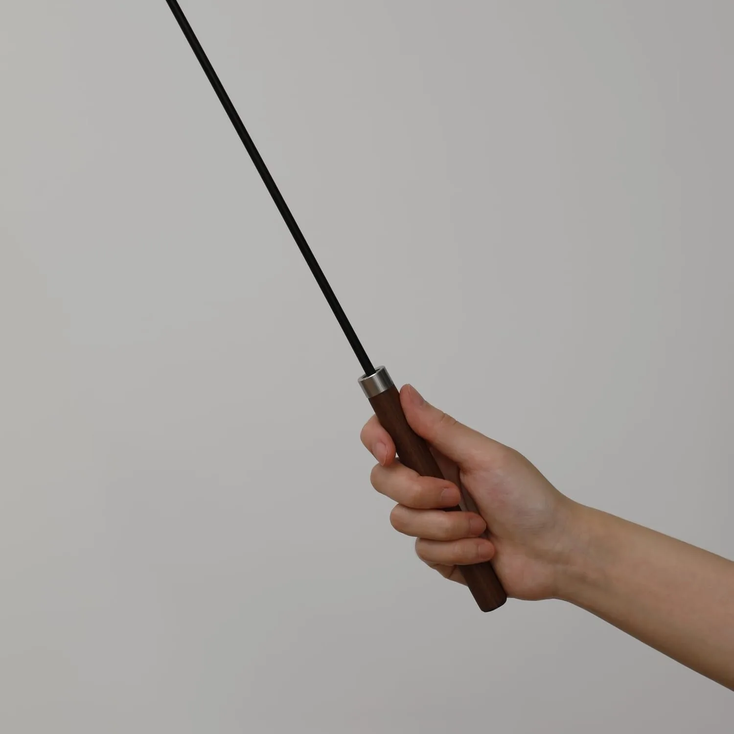 A hand gripping The Chaser's walnut handle at the steel ferrule